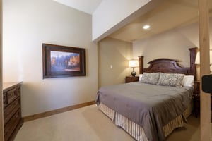 The serene bedroom at Jupiter Inn 10 features a comfortable queen bed and warm, understated decor — the perfect place to recharge during your Park City vacation rental stay.