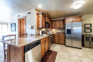 The fully equipped kitchen at Jupiter Inn 17 boasts stainless steel appliances, granite countertops, and rich wood cabinetry — everything you need to feel at home in this Park City vacation rental.