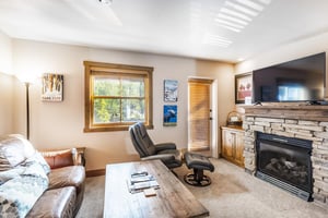 Cozy up by the stone fireplace in the living room at Jupiter Inn 18, complete with a flatscreen TV and comfortable seating. A warm and inviting space that makes this Park City condo rental feel like 