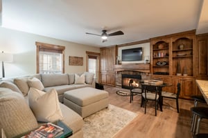 Cozy up by the fireplace in Resort Plaza 5002 — your perfect Park City vacation rental featuring warm wood accents, a spacious sectional, and all the comforts of home after a day on the slopes.