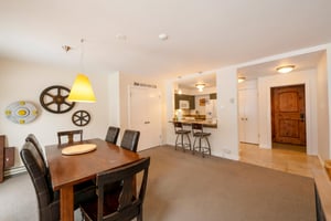 Gather around the warm wood dining table at Resort Plaza 5007 — this inviting Park City vacation rental features a spacious dining area with an open flow into the kitchen and bar seating, perfect for