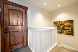 The charming entryway and staircase at Resort Plaza 5007 set the tone for a wonderful stay — this beautifully detailed Park City vacation rental welcomes you with a stunning rustic wood door and brigh