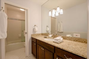 Fresh and beautifully finished, this bathroom at Resort Plaza 5007 features a granite vanity, rich dark wood cabinetry, and a tiled shower — all the touches that make this Park City vacation rental fe