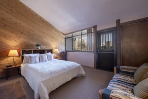 A bright and spacious bedroom at Park Avenue 243 combines rustic woodpaneled walls with large windows.