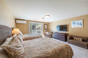 This generously sized double queen bedroom features balcony access, a flatscreen TV, and warm, comfortable furnishings for a relaxing stay. Everything you need for a restful night at this Park City v