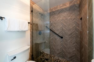 This beautifully tiled walkin shower features stunning chevron tilework and sleek matte black fixtures, adding a touch of modern elegance to the bathroom at this Park City vacation rental.