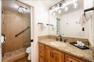This wellappointed bathroom features warm wood cabinetry, granite countertops, and a beautifully tiled walkin shower, offering a clean and comfortable space for guests during their Park City vacatio