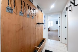 This thoughtfully designed mudroom entry features a custom wood wall with builtin hooks and a boot tray, making it the perfect space to store gear after a day on the mountain. A practical and stylish