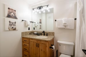 Classic wood finishes and granite countertops give this tidy bathroom a warm and inviting character, reflecting the careful attention to detail found throughout this Park City lodging experience at Re