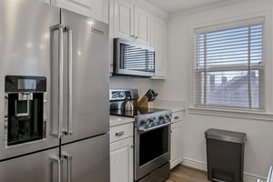 Your fully equipped kitchen features stainless steel appliances, crisp white cabinetry, and natural light from a large window—perfect for preparing your favorite meals.