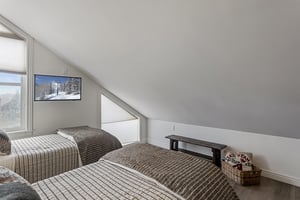 Unwind in your cozy loft bedroom with two twin beds, perfect for a restful mountain retreat. Natural light and alpine views create a serene space.