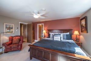 The stunning king bedroom at Resort Plaza 5064 impresses with a rich accent wall, beautiful wooden bed frame, and warm ambient lighting, making this Park City condo rental a truly luxurious mountain r
