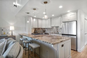 The showstopping kitchen and breakfast bar at Three Kings 64 feature stunning granite countertops, elegant pendant lighting, and premium appliances, creating a sophisticated gathering space that makes