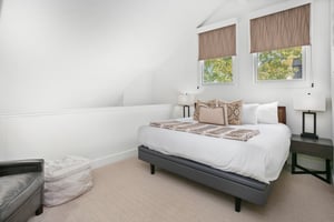 The charming loft king bedroom at Three Kings 64 offers a bright and airy retreat with vaulted ceilings, soft natural light, and cozy furnishings that add a unique and delightful touch to this wonderf