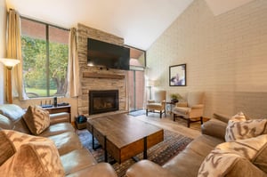 The warm and inviting living room at Park Avenue 256 features a stunning stone fireplace, vaulted ceilings, and comfortable furnishings — a classic mountain retreat that defines quality.