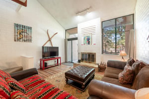 Rustic charm is featured in the cozy sitting area at Park Avenue 333. Natural wood accents, a classic fireplace, and treetop views create a warm atmosphere that makes this Park City vacation rental fe