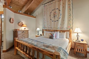 Drift off in comfort in the cozy king bedroom at 1296 Pinnacle — a charming Deer Valley vacation rental where rustic log furnishings and vaulted wood ceilings create the ultimate mountain retreat.