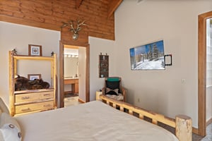 This inviting bedroom at 1296 Pinnacle features a wallmounted smart TV and a private ensuite bath — a perfect combination of comfort and convenience.