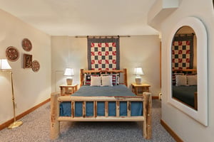 Charming and cozy, this rustic log queen bedroom at 1296 Pinnacle features warm handcrafted furnishings and unique quilt wall art.