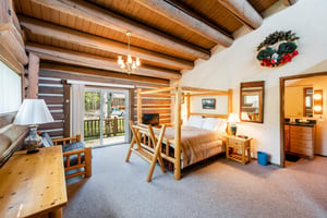 Charming and spacious, this inviting bedroom at Temptation 8 features rustic log furnishings, exposed wood beam ceilings, and private deck access — a delightful retreat within this cozy Park City vaca