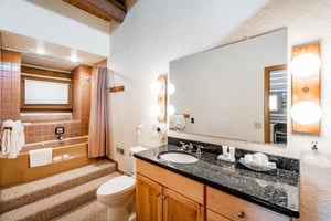 Clean and wellappointed, this full bathroom at Temptation 8 features dark granite countertops, warm wood cabinetry, and a tub and shower combo.