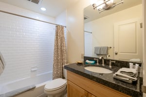 Three Kings 37 offers a clean and stylish bathroom featuring classic white subway tile, dark granite countertops, and warm wooden cabinetry that perfectly complement this outstanding Park City vacatio