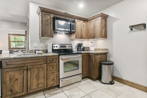 Your fully equipped kitchen features rustic wood cabinetry, granite countertops, and modern appliances including a stove, microwave, and coffee maker—everything you need in the perfect Park City vacat