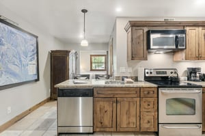 A wellequipped kitchen with wood cabinetry, stainless steel appliances, and granite countertops — everything you need to cook in during your Park City vacation rental stay.