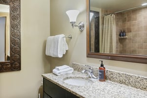 A clean, wellappointed bathroom with a granite vanity, plush towels, and a spacious tiled shower.