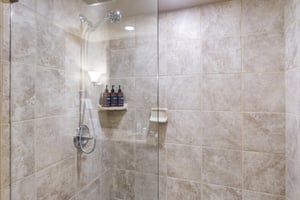 Step into your spacious walkin shower with dual rainfall and handheld fixtures, premium toiletries at your fingertips, and elegant stone tile that invites pure relaxation.