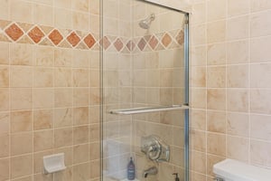 Tiled walkin shower at Resort Plaza 5064s ensuite, framed by a decorative diamond tile accent and a sleek glass door.