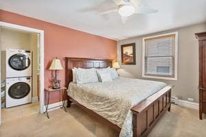 The stunning king bedroom at Resort Plaza 5064 impresses with a rich accent wall, beautiful wooden bed frame, and warm ambient lighting, making this Park City condo rental a truly luxurious mountain r