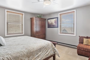 Guest bedroom at Resort Plaza 5064 with a plush king bed, warm wood armoire, and mountain art print for a cozy retreat.