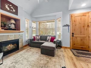 Settle in beside the fireplace with a book or good conversation—this cozy living space welcomes you with warm wood accents, natural light, and a soft sofa perfect for relaxing after a day of adventure