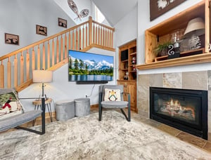 Settle into this inviting living space where rustic charm meets modern comfort. Cozy seating invites you to unwind by the crackling fireplace, while vaulted ceilings and natural light create an airy m