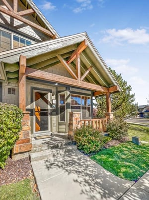 The property entrance features craftsmanstyle architecture with natural wood beams and a welcoming covered porch surrounded by landscaped gardens. The neighborhood offers a peaceful residential setti