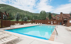 A tranquil outdoor pool surrounded by lush green hills and mountain views, offering a refreshing retreat under open skies in a peaceful alpine setting.