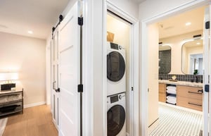 Your laundry stays effortless with a stacked washer and dryer tucked neatly behind sleek barn doors—vacation convenience without sacrificing style.