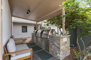 Outdoor grills next to chairs on a covered patio at Destin Beach Club