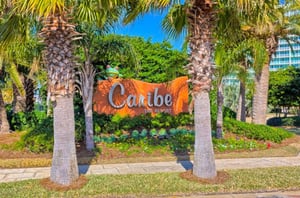 The propertys entrance sign surrounded by a tropical landscape