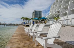 Adirondack chairs seated along the boardwalk next to the adjacent harbor.
