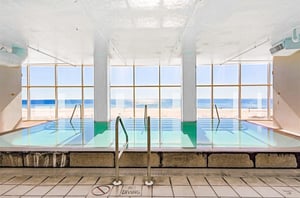 The indoor swimming pool next to floor to ceiling windows overlooking the beach at Island Tower