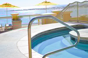 The complexs hot tub, sun deck, and loungers beside Destin Pass and the Gulf of Mexico.