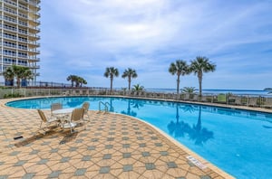 Large outdoor swimming pool and deck next to the Gulf of Mexico and Beach Colony Resort highrise
