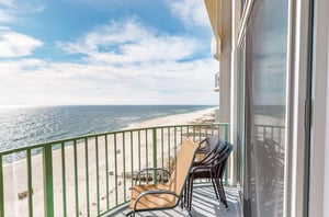 View down the coast from a private balcony with a chair and table