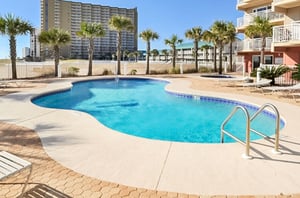 The complexs irregularshaped swimming pool sparkles under blue skies.