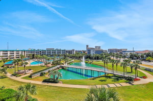 Two sparkling pools, a large pond and towering palms dot the complexs tropical landscape.