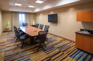 A conference table surrounded by chairs with a TV behind the table at Fairfield Inn and Suites in Orange Beach Alabama