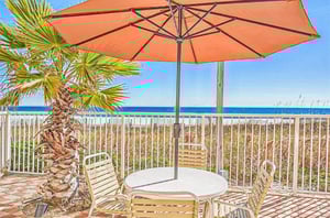 A table and chairs next to the beach at the Enclave