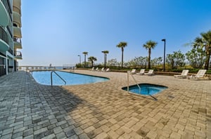 The outdoor pool and hot tub surrounded by lounge chairs at Grand Point in Orange Beach Alabama